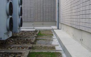 Area tecnica con sistemi di ventilazione industriale e barriere fonoassorbenti in cemento.