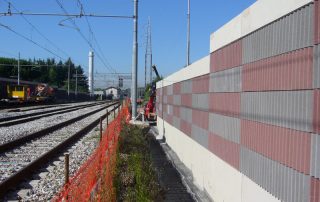 Dettaglio di una barriera fonoassorbente "Paver Sound" con superficie a rilievo in cemento e inserti colorati.
