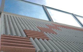 Dettaglio di una barriera fonoassorbente "Paver Sound" con superficie a rilievo in cemento e inserti colorati.