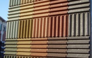 Dettaglio di una barriera fonoassorbente "Paver Sound" con superficie a rilievo in cemento e inserti colorati.