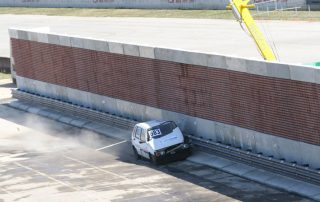 Una macchina durante un crash test impatta contro una barriera fonoassorbente "Paver Sound Integra", dimostrando la resistenza della struttura.