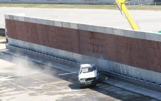 Una macchina durante un crash test impatta contro una barriera fonoassorbente "Paver Sound Integra", dimostrando la resistenza della struttura.