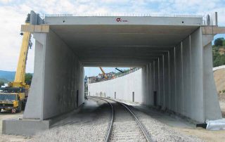 Galleria artificiale prefabbricata in cemento armato in fase di costruzione sopra una linea ferroviaria.