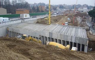 Cantiere di costruzione di una galleria artificiale con struttura in cemento armato prefabbricato.