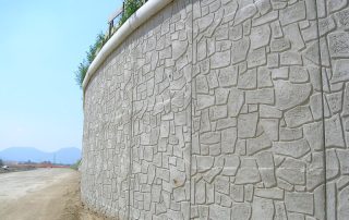 Muro di sostegno prefabbricato in calcestruzzo con finitura effetto pietra.