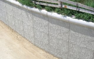 Muro di sostegno prefabbricato in calcestruzzo con finitura effetto pietra.