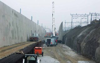 Muro di sostegno prefabbricato in cemento armato installato lungo un'area di scavo.