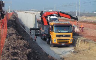 Muro di sostegno prefabbricato in cemento armato installato lungo un'area di scavo.
