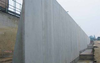Muro di sostegno prefabbricato in cemento armato installato lungo un'area di scavo.