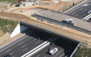 Veduta aerea di un cavalcavia in costruzione sopra un'autostrada a più corsie.