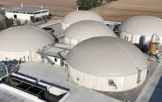 Veduta aerea di un impianto di biogas con più biodigestori coperti.