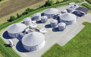 Veduta aerea di un impianto di biogas con più biodigestori cilindrici coperti.