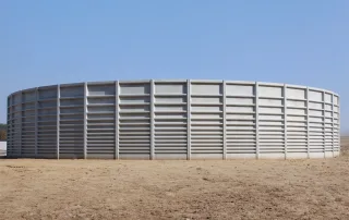 Vasca agricola circolare in metallo per lo stoccaggio di liquami, con struttura rinforzata a pannelli. L'installazione si trova in un'area aperta con terreno asciutto.