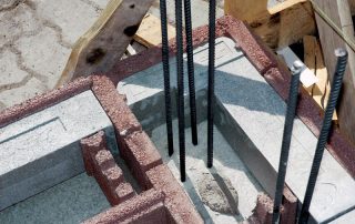 Struttura in costruzione con blocchi BioPLUS®. Barre di armatura in acciaio emergono verticalmente dalla base.