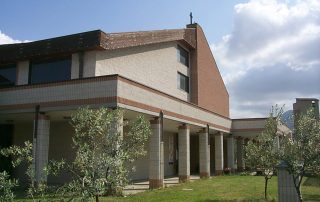 Edificio moderno con porticato, colonne in piastrelle e tetto inclinato in mattoni,