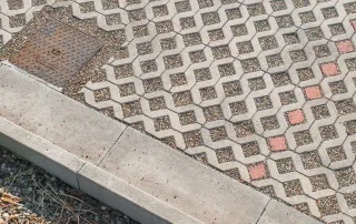 Cordolo in cemento delimitante un'area pavimentata con grigliati in calcestruzzo.
