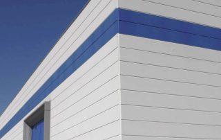 Edificio industriale con pareti prefabbricate in calcestruzzo, finitura esterna liscia con fasce decorative blu.