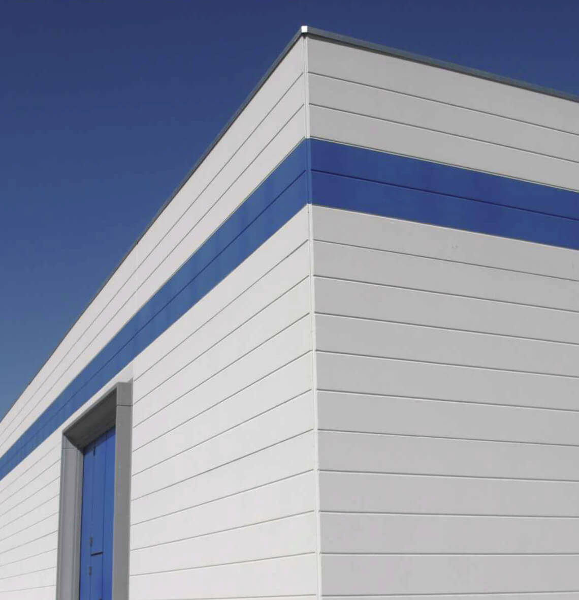 Edificio industriale con pareti prefabbricate in calcestruzzo, finitura esterna liscia con fasce decorative blu.