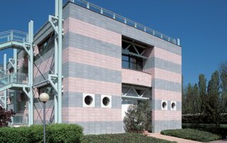 Edificio con facciata a fasce orizzontali realizzate con blocchi di Lecablocco grigi e rosa.