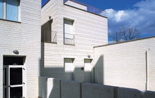 Edifici residenziali con facciate esterne realizzate in Lecablocco bianco, con diverse aperture e un piccolo balcone.