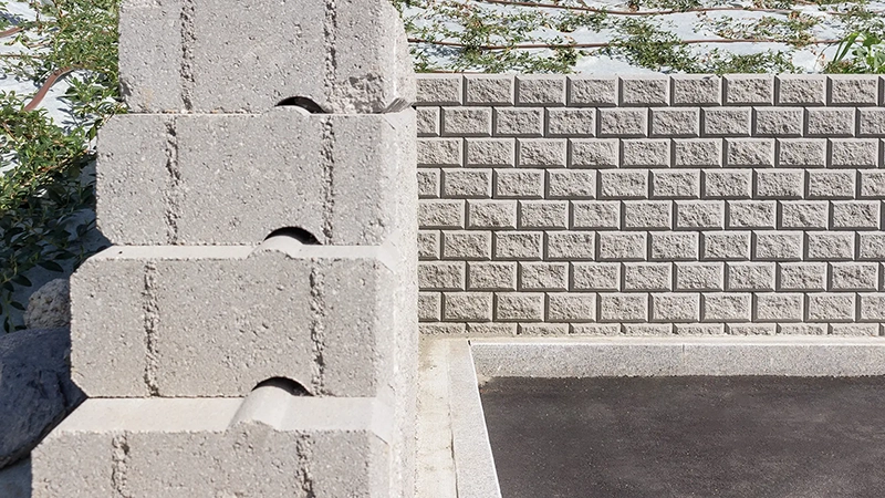 Dettaglio di un muro di contenimento in blocchi Muricciolo grigi, con vista frontale e laterale che evidenzia l'incastro tra gli elementi modulari.