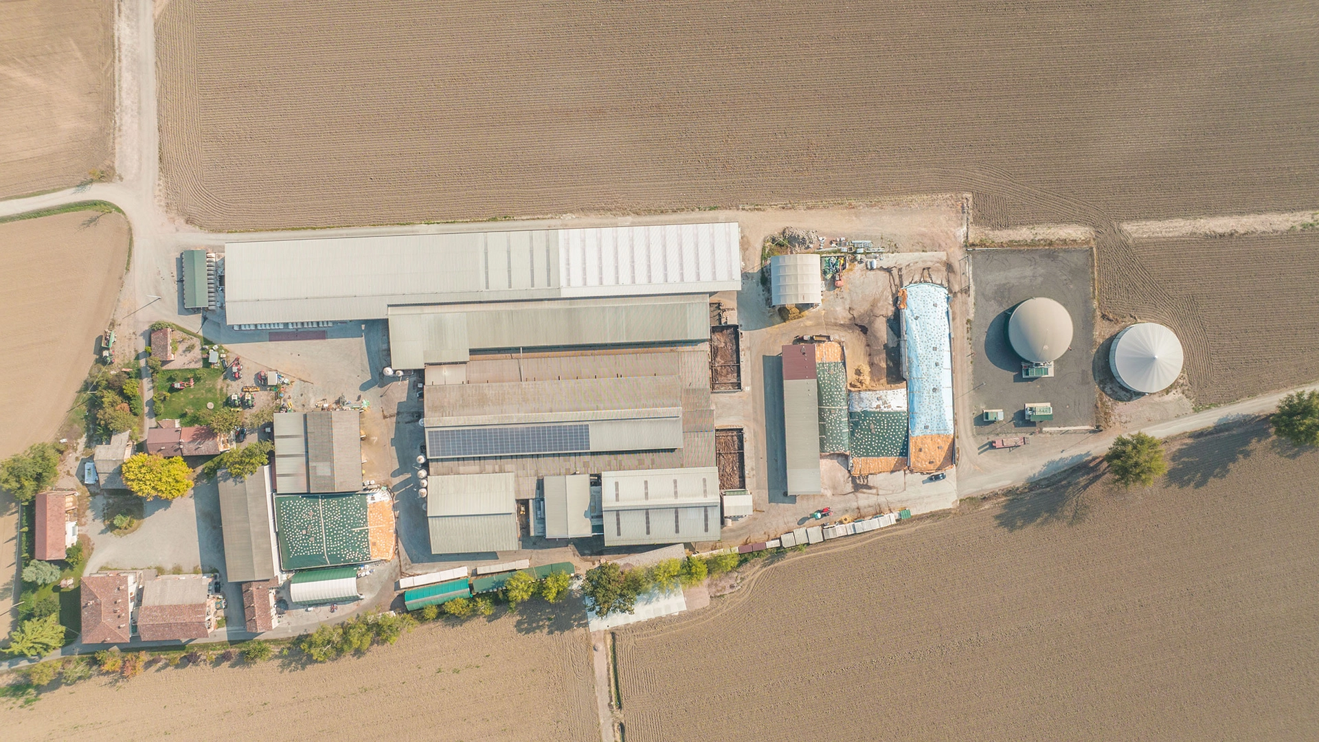 Vista aerea di un'azienda agricola con impianto di biogas, capannoni industriali e aree di stoccaggio.