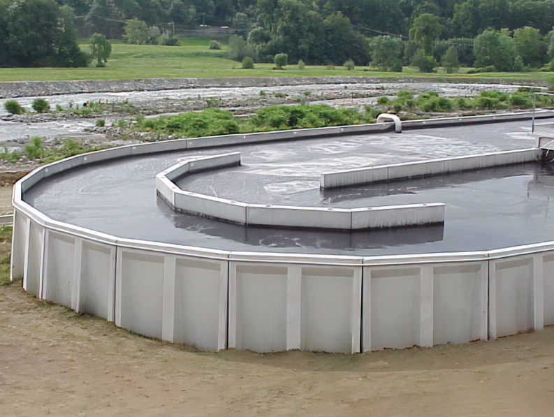 Una grande vasca industriale di forma rettangolare. La vasca contiene un liquido scuro e denso.