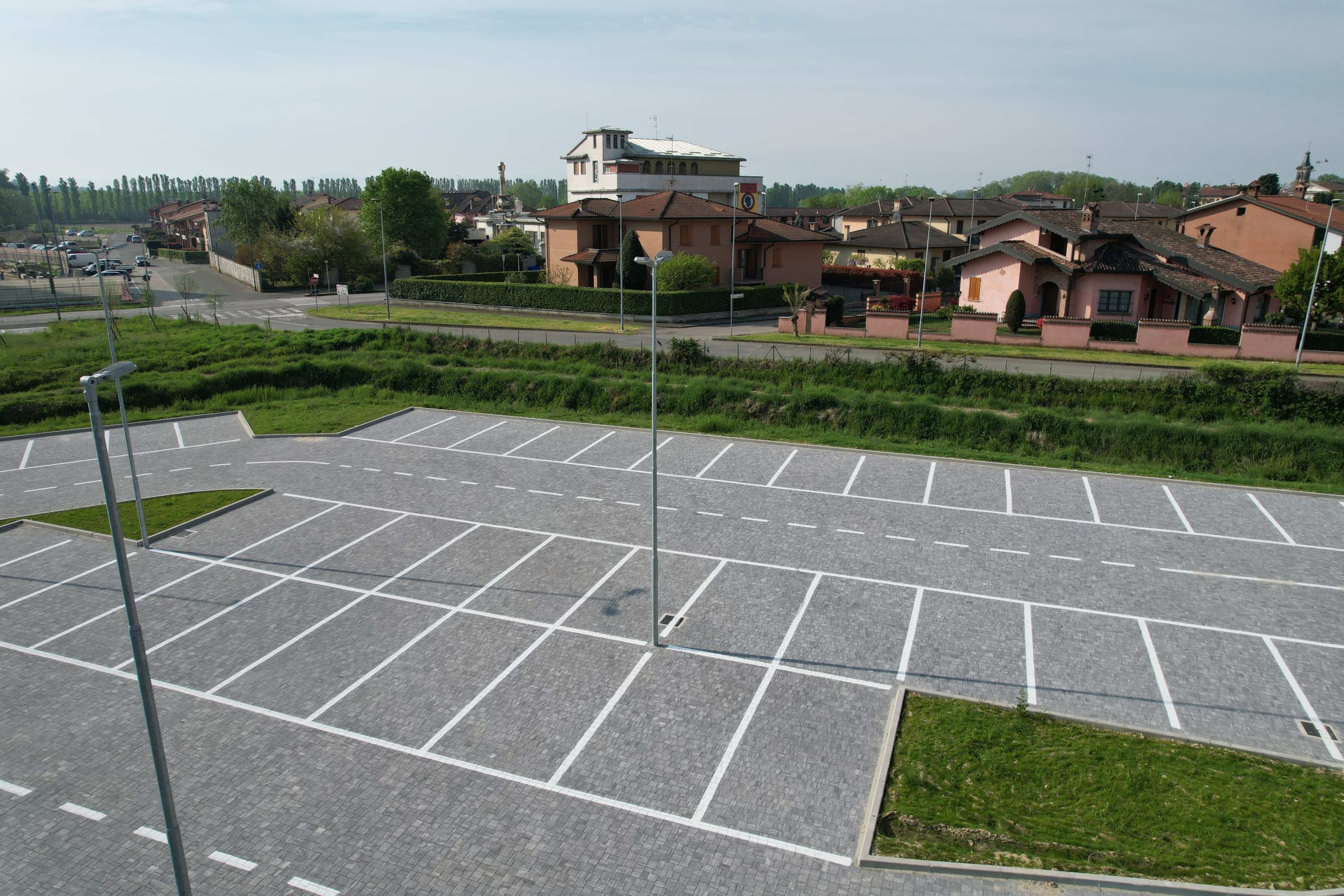 Pavimentazione in blocchetti di pietra grigia in un parcheggio con segnaletica bianca.