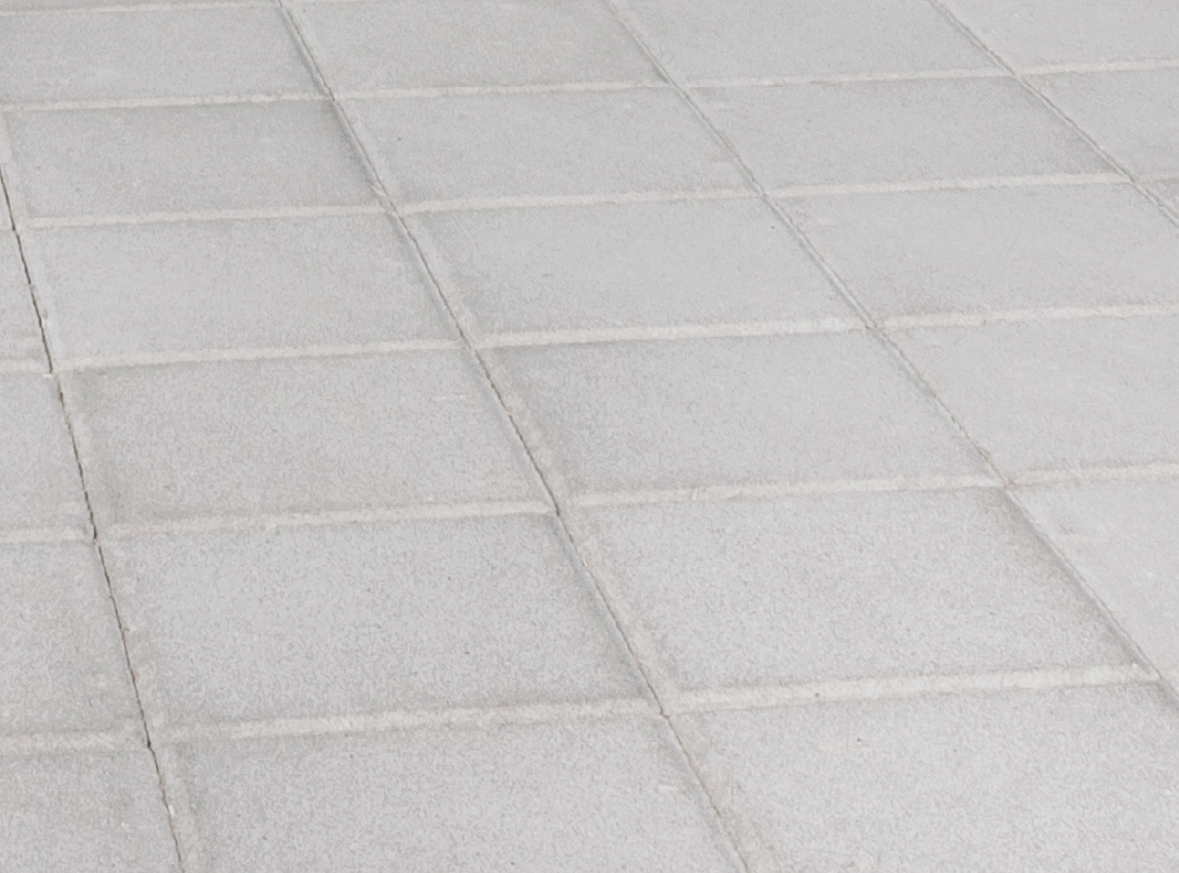 Pavimentazione in cemento modello "Aurelia", con superficie liscia e formato quadrato con fughe regolari, di colore grigio chiaro.