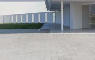 Pavimentazione in cemento modello "Aurelia", con superficie liscia e formato quadrato con fughe regolari, di colore grigio chiaro.