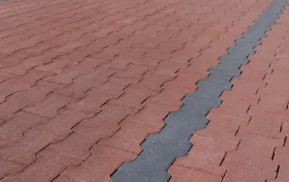Pavimentazione in blocchi autobloccanti a incastro, con colori alternati tra rosso e grigio.