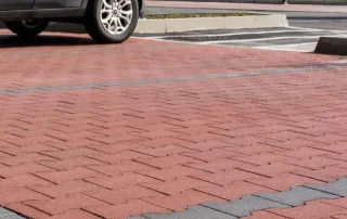 Pavimentazione in blocchi autobloccanti a incastro, con colori alternati tra rosso e grigio.