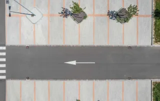 Parcheggio pavimentato con blocchi rettangolari in cemento e dettagli in mattoncini colorati, visto dall'alto.