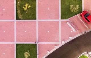 Piazza pavimentata con blocchi rettangolari in cemento e dettagli in prato verde.