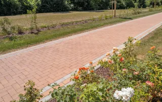 Sentiero pavimentato con blocchi in cemento color mattone e bordi chiari.