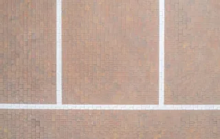 Pavimentazione in selciato con blocchi rettangolari disposti in modo regolare, con linee bianche che delimitano delle sezioni.