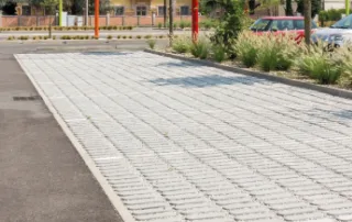 Pavimentazione drenante in cemento con blocchi rettangolari e fughe in ghiaia.