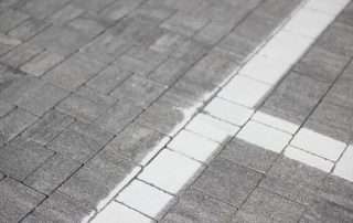 Pavimentazione in blocchetti di pietra grigia con una linea bianca segnaletica.