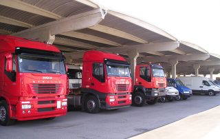 Parcheggio coperto con struttura prefabbricata in cemento, utilizzato per il rimessaggio di camion e veicoli commerciali.