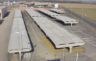 Parcheggio coperto con strutture prefabbricate in cemento e coperture ondulate.