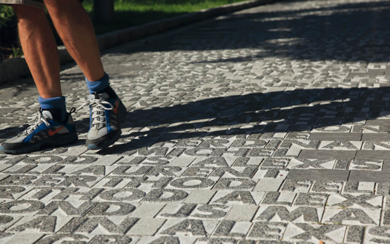 Pavimentazione in pietra con incisioni testuali bianche su sfondo grigio scuro