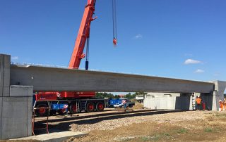 Posizionamento di una trave prefabbricata in cemento armato per la costruzione di un ponte.