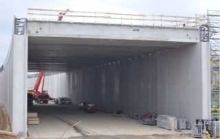 Costruzione di un tunnel, con pareti prefabbricate in cemento armato e armature metalliche in fase di installazione.