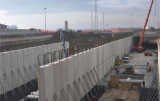 Costruzione di un sottopasso stradale, con pareti prefabbricate in cemento armato e armature metalliche in fase di installazione.