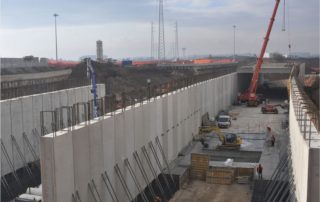 Costruzione di un sottopasso stradale, con pareti prefabbricate in cemento armato e armature metalliche in fase di installazione.