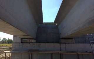 Vista ravvicinata dell’installazione delle travi prefabbricate per un ponte in costruzione.