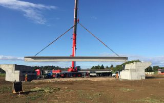 Posizionamento di una trave prefabbricata in cemento armato per la costruzione di un ponte.