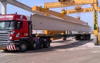 Posizionamento di una trave prefabbricata in cemento armato per la costruzione di un ponte.