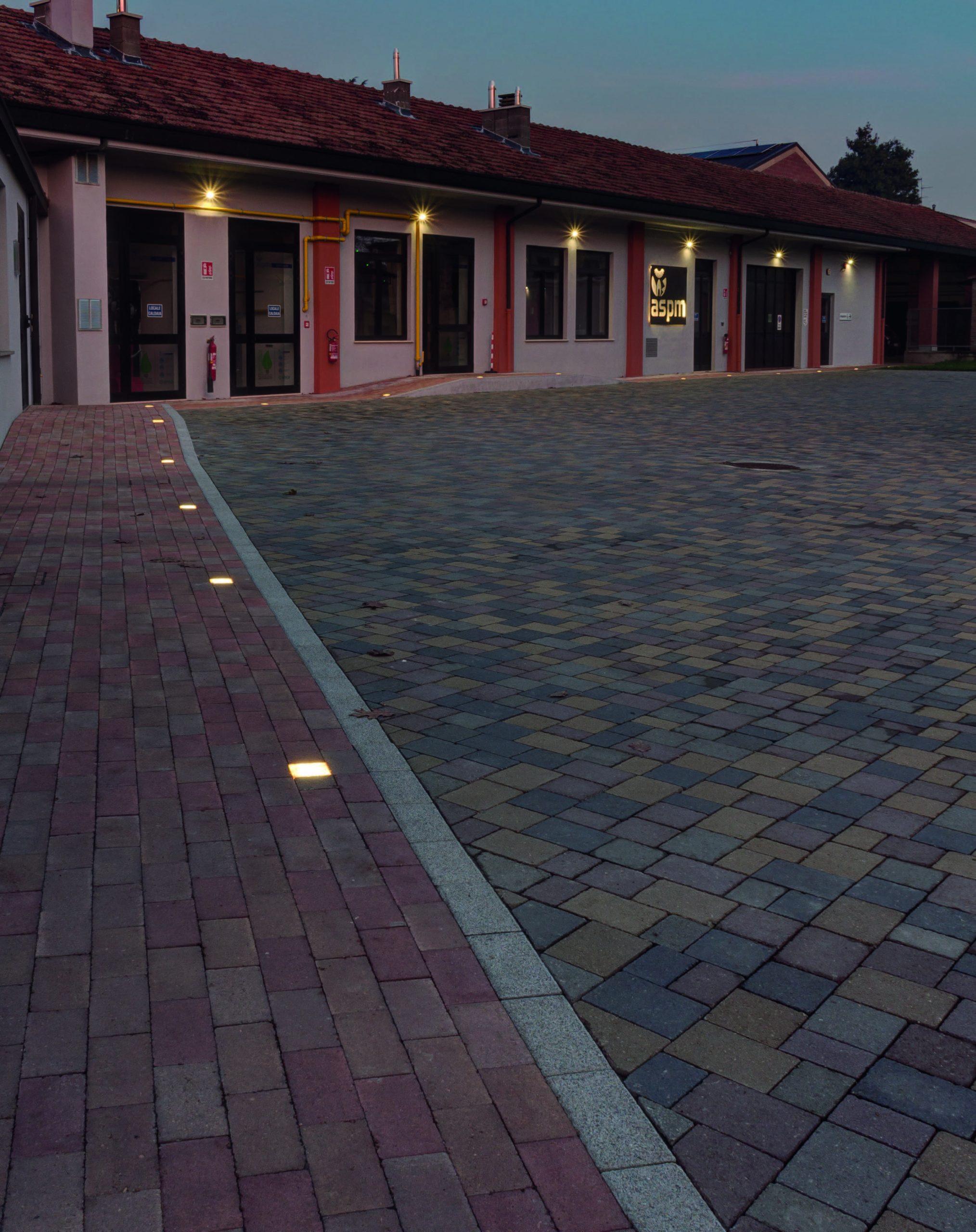 Cortile pavimentato con blocchi autobloccanti e illuminazione LED incassata a terra.