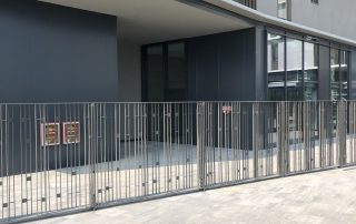 Pavimentazione in autobloccanti Paver Londra a Cascina Merlata, con recinzione metallica e facciata vetrata riflettente.